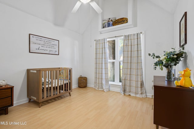 bedroom featuring ceiling fan, high vaulted ceiling, hardwood / wood-style flooring, and a crib