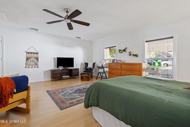 bedroom featuring light hardwood / wood-style floors, crown molding, a textured ceiling, and ceiling fan