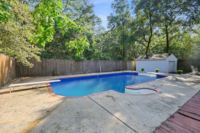 view of swimming pool featuring a shed, a patio, and a diving board