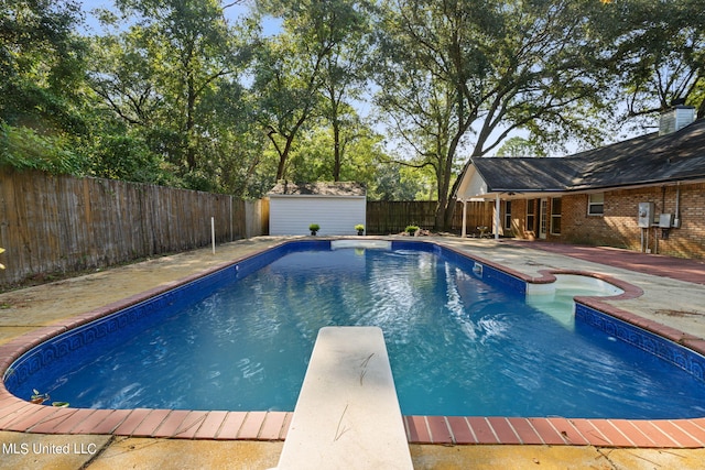 view of pool featuring a patio area, a shed, and a diving board