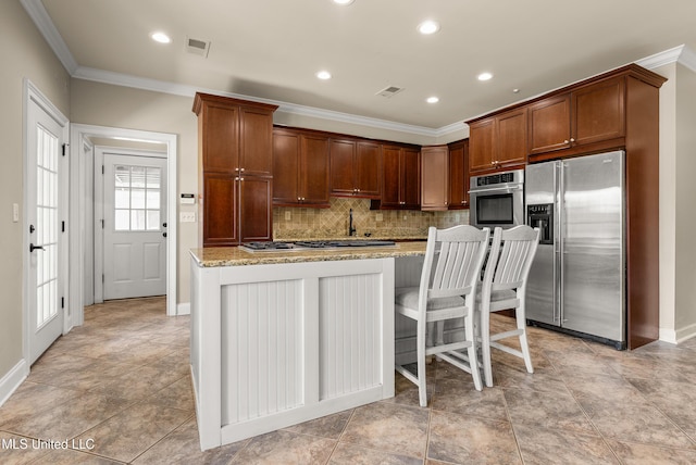 445 Carey Chapel Rd, Red Banks, MS 38661 - kitchen featuring appliances with stainless steel finishes, crown molding, backsplash, light stone counters, and a kitchen island