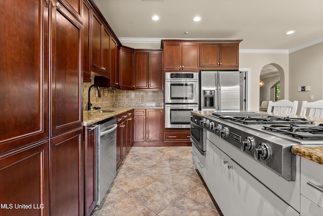 445 Carey Chapel Rd, Red Banks, MS 38661 - kitchen with stainless steel appliances, arched walkways, light stone countertops, tasteful backsplash, and crown molding