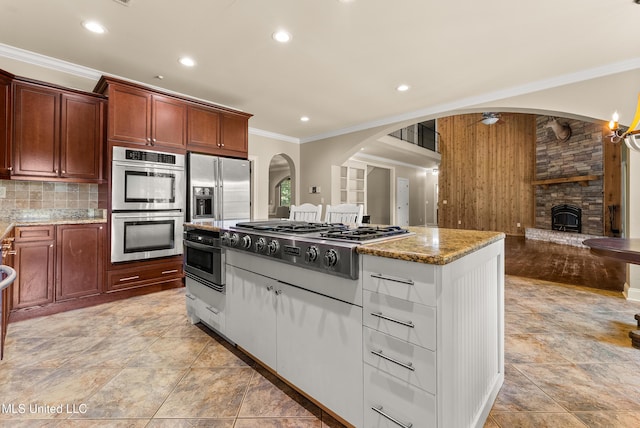 445 Carey Chapel Rd, Red Banks, MS 38661 - kitchen with stainless steel appliances, ornamental molding, light stone countertops, a fireplace, and arched walkways