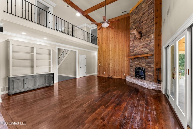 445 Carey Chapel Rd, Red Banks, MS 38661 - unfurnished living room featuring a towering ceiling, a fireplace, hardwood / wood-style floors, a ceiling fan, and wooden walls