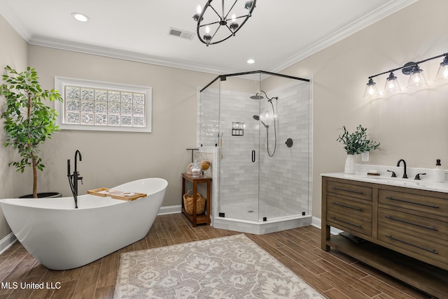 445 Carey Chapel Rd, Red Banks, MS 38661 - bathroom featuring wood finished floors, a stall shower, a soaking tub, a chandelier, and ornamental molding