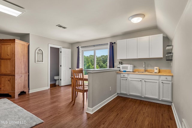 445 Carey Chapel Rd, Red Banks, MS 38661 - kitchen with dark wood finished floors, light countertops, white cabinetry, and white microwave
