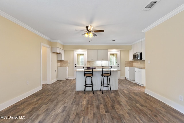 kitchen featuring dark wood-type flooring, a center island, a breakfast bar area, and white cabinets