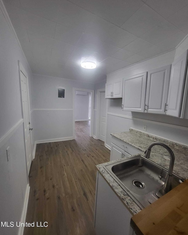 kitchen featuring dark wood-type flooring, crown molding, sink, and white cabinets