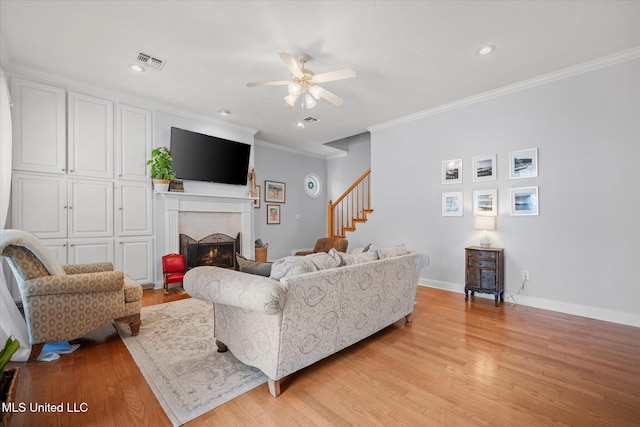25 Savannah Cir, Brandon, MS 39047 - living area with ceiling fan, ornamental molding, stairway, light wood-style floors, and a lit fireplace