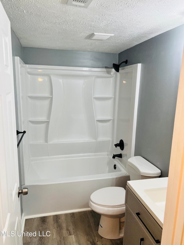 full bathroom featuring vanity, wood-type flooring, a textured ceiling, and toilet