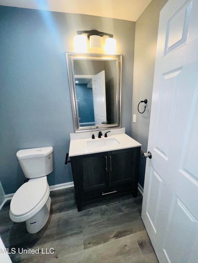 bathroom with wood-type flooring, vanity, and toilet