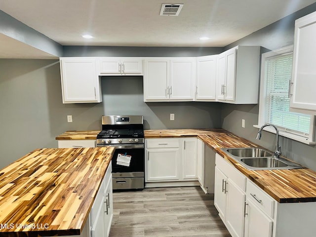 kitchen with white cabinetry, stainless steel gas range oven, butcher block counters, and sink