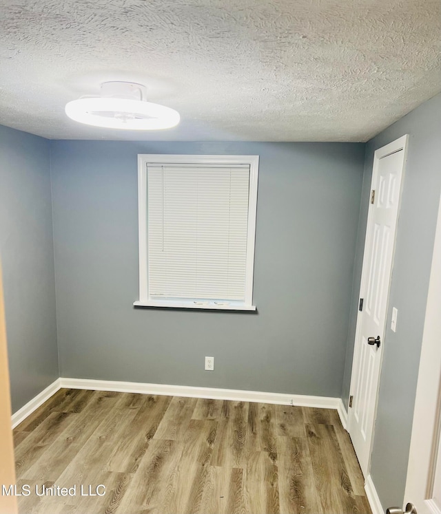 unfurnished room featuring wood-type flooring and a textured ceiling