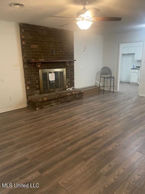 unfurnished living room featuring ceiling fan, wood finished floors, baseboards, and a brick fireplace
