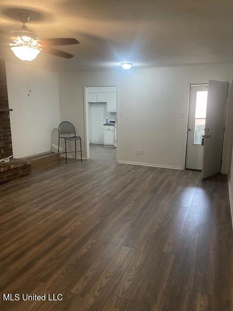 unfurnished living room with a ceiling fan, dark wood-style floors, and baseboards