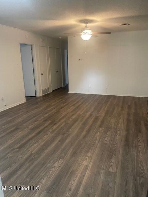 empty room featuring dark wood-style flooring, ceiling fan, and baseboards