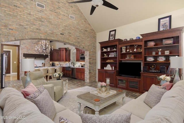 living area featuring high vaulted ceiling, visible vents, arched walkways, and ceiling fan with notable chandelier