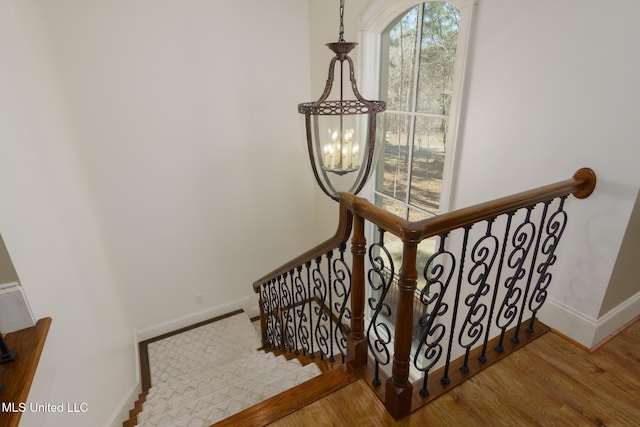 staircase featuring a healthy amount of sunlight, baseboards, and wood finished floors