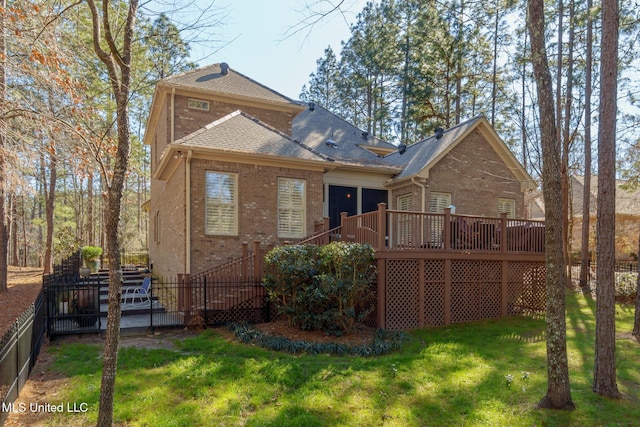 back of property featuring brick siding, a lawn, a wooden deck, and fence