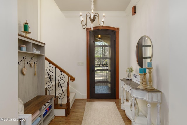 foyer entrance featuring stairs, a chandelier, and wood finished floors