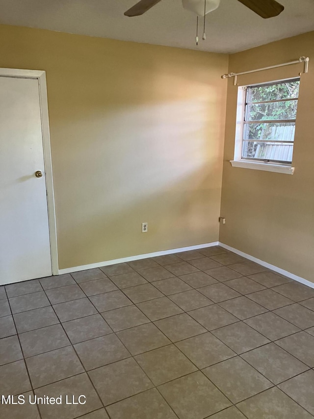 empty room featuring a ceiling fan, tile patterned flooring, and baseboards