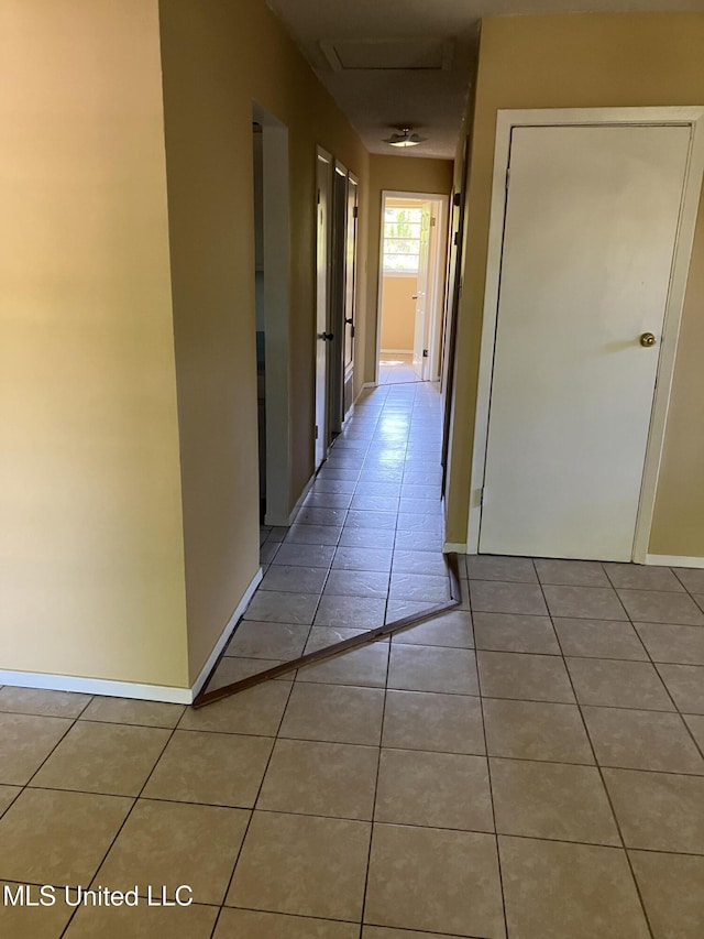 corridor featuring tile patterned flooring and baseboards