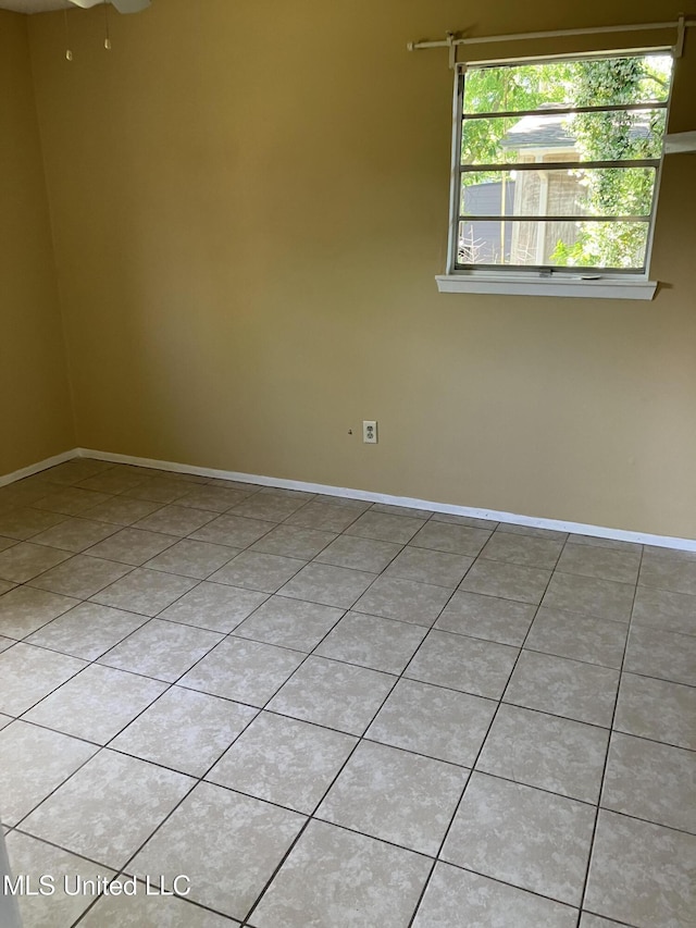 spare room featuring light tile patterned floors and baseboards