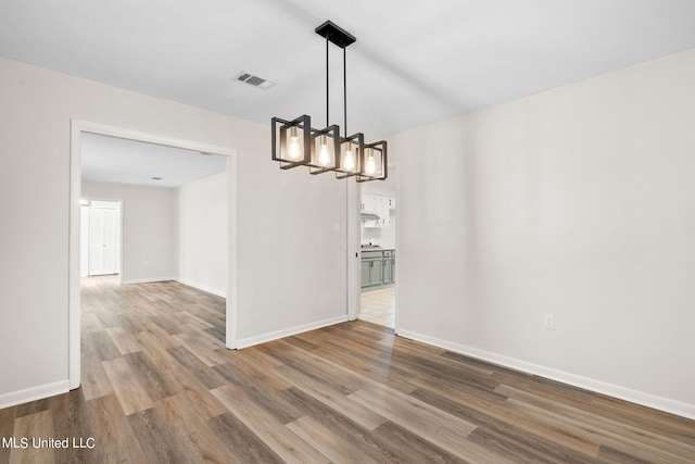 unfurnished dining area with a chandelier and wood-type flooring