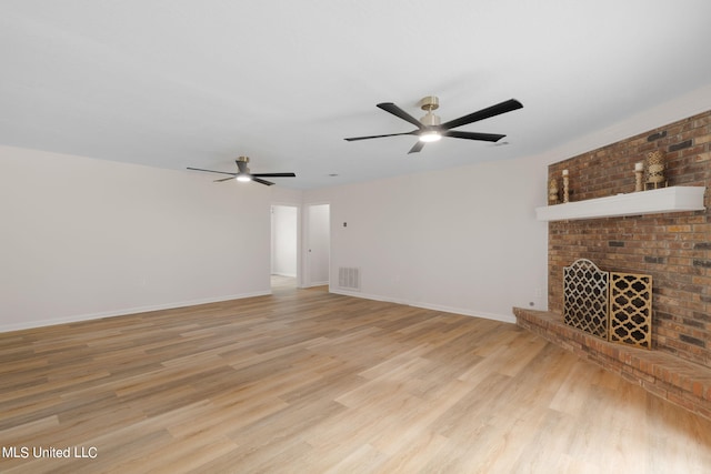 unfurnished living room with light hardwood / wood-style floors, ceiling fan, and a brick fireplace