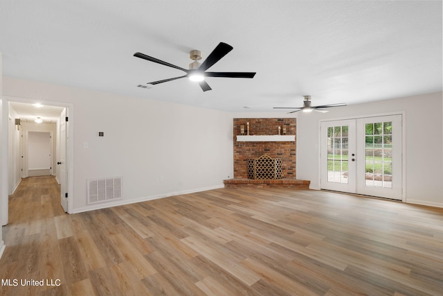 unfurnished living room with light hardwood / wood-style floors, french doors, a fireplace, and ceiling fan