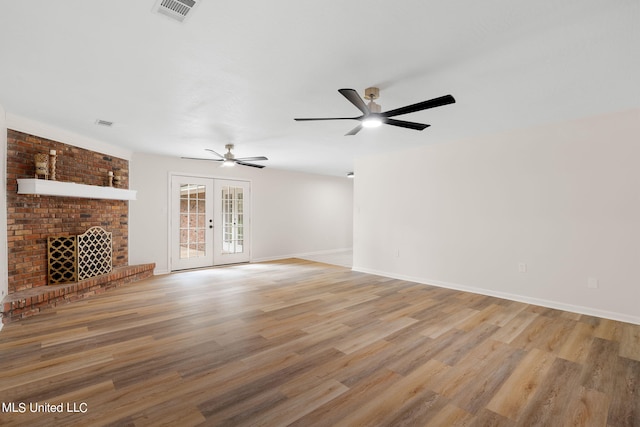 unfurnished living room featuring french doors, ceiling fan, light wood-type flooring, and a fireplace