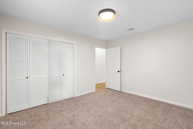 unfurnished bedroom featuring a closet and light colored carpet