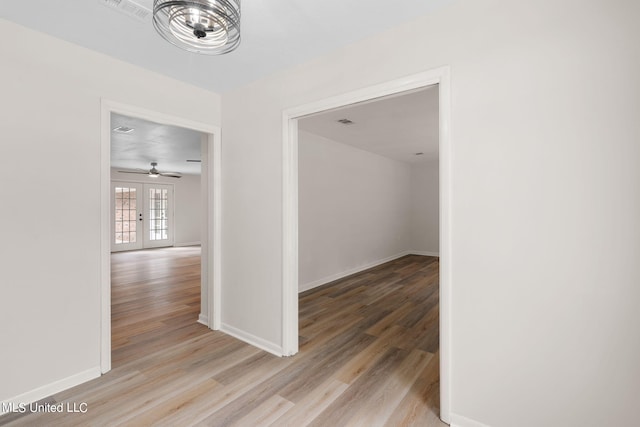 corridor with french doors and light hardwood / wood-style floors