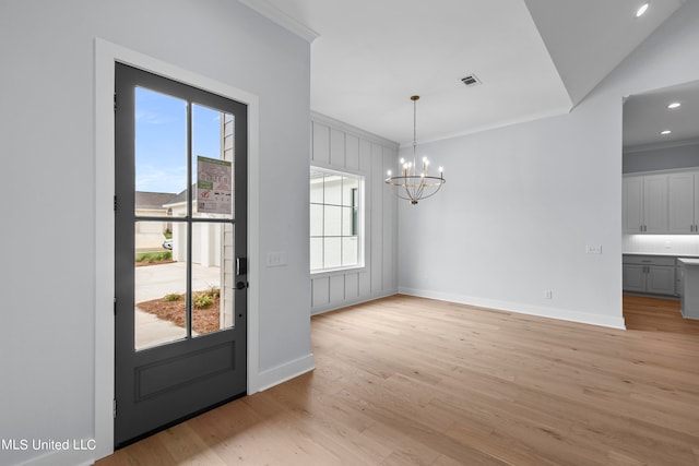 unfurnished dining area with light hardwood / wood-style floors, crown molding, a chandelier, and lofted ceiling