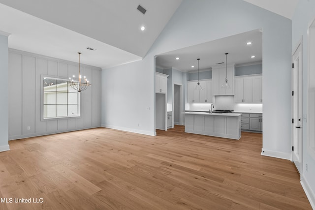 unfurnished living room featuring light hardwood / wood-style flooring, a chandelier, and high vaulted ceiling