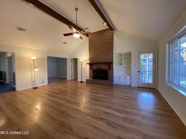 790 Ewa Pl, Diamondhead, MS 39525 - unfurnished living room with a brick fireplace, beam ceiling, a ceiling fan, wood finished floors, and high vaulted ceiling