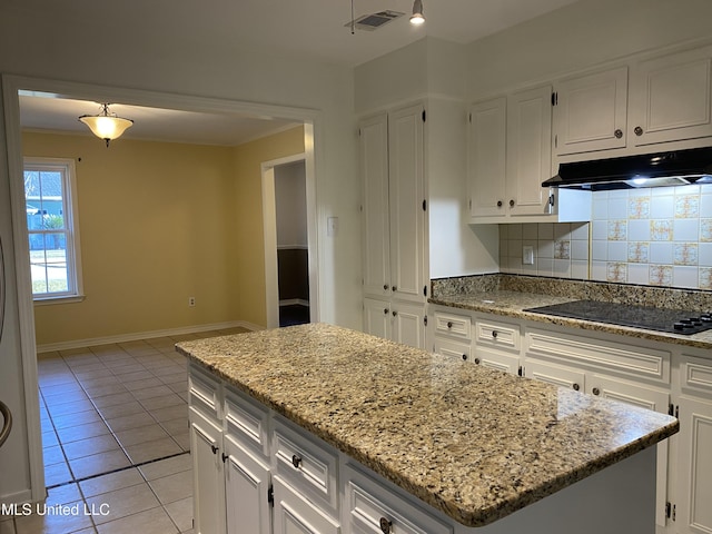 790 Ewa Pl, Diamondhead, MS 39525 - kitchen with black electric stovetop, under cabinet range hood, white cabinets, a kitchen island, and backsplash