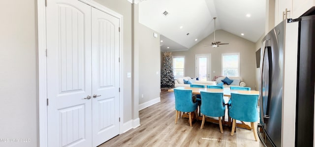 dining space featuring light wood finished floors, visible vents, baseboards, a ceiling fan, and vaulted ceiling