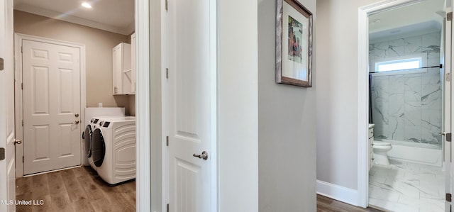 laundry room featuring crown molding, cabinet space, wood finished floors, independent washer and dryer, and baseboards