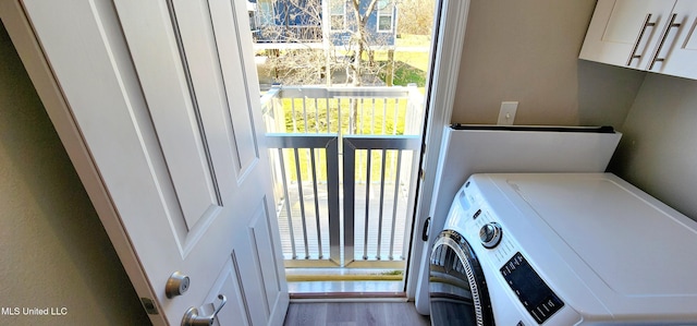 laundry room with washer / dryer, cabinet space, a wealth of natural light, and wood finished floors