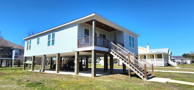 rear view of property with a patio area, a yard, and stairs