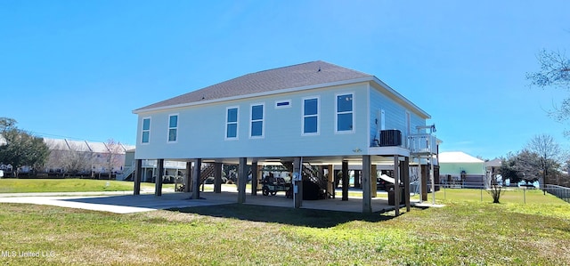 back of house with a lawn, stairway, roof with shingles, fence, and a carport