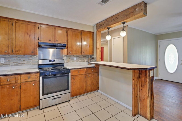 428 Simpson Cir, Mendenhall, MS 39114 - kitchen with stainless steel gas range, under cabinet range hood, brown cabinetry, decorative backsplash, and a peninsula