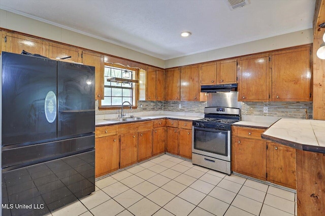 428 Simpson Cir, Mendenhall, MS 39114 - kitchen with stainless steel range with gas stovetop, under cabinet range hood, freestanding refrigerator, a sink, and brown cabinetry