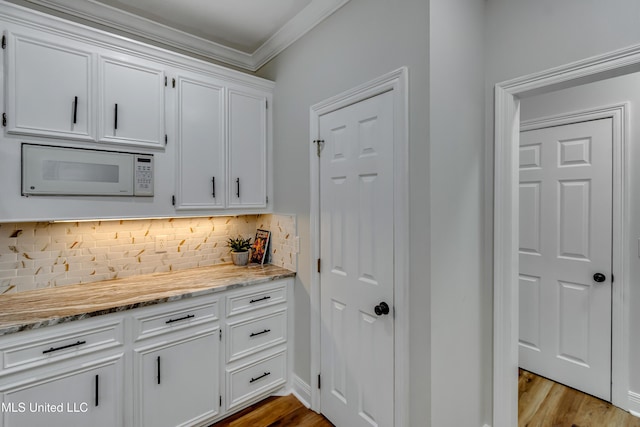105 Lilac Ct, Madison, MS 39110 - kitchen featuring white microwave, white cabinetry, backsplash, wood finished floors, and light stone counters