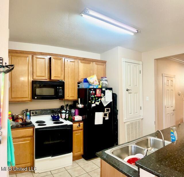 kitchen with sink, dark stone countertops, black appliances, and light tile patterned floors