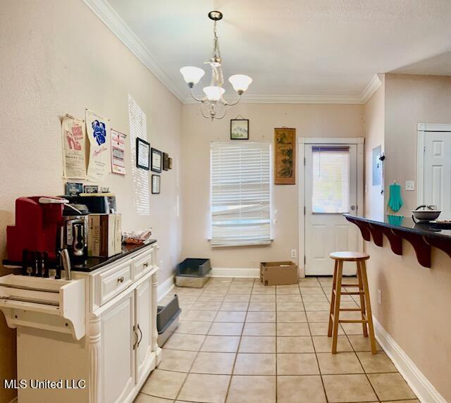 kitchen with a notable chandelier, light tile patterned floors, hanging light fixtures, and crown molding