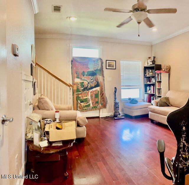 living room with hardwood / wood-style floors, crown molding, and ceiling fan