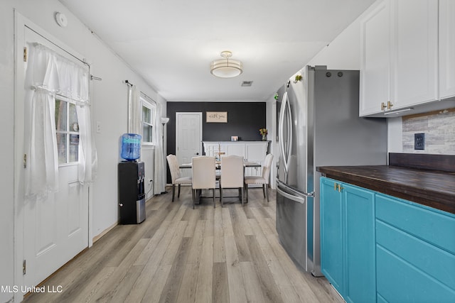 kitchen featuring tasteful backsplash, wooden counters, blue cabinets, white cabinets, and light wood-type flooring