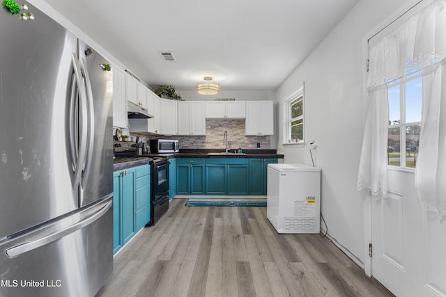 kitchen with blue cabinetry, stainless steel appliances, white cabinets, and plenty of natural light